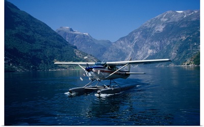 A seaplane lands on the blue waters of Geirangerfjord