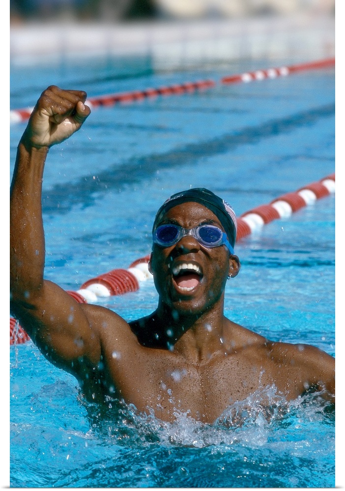 portrait of a young male swimmer raising his hands in victory