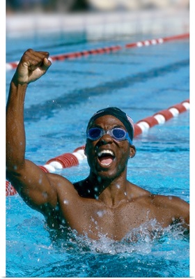 A young male swimmer raising his hands in victory