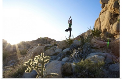 A young woman practices yoga on a rock outdoors in California.