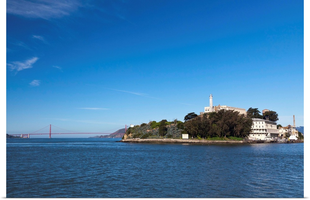Alcatraz island and rock and Golden Gate bridge on bright and sunny day.