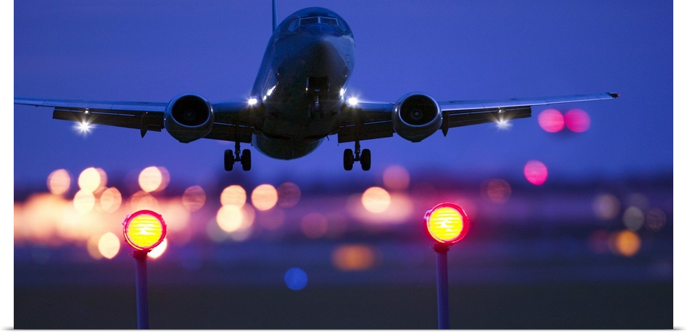 Composite close-up of an airplane landing with blurred lights of the airport in the background