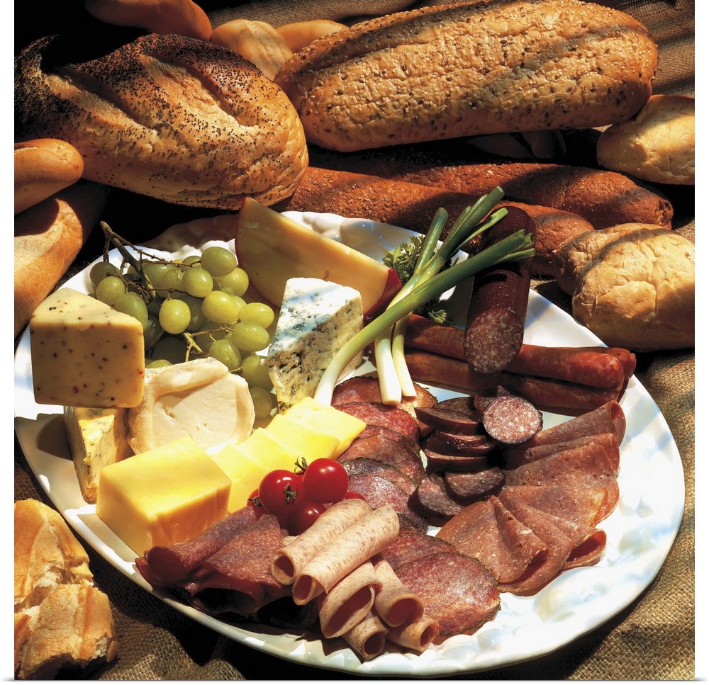 an array of assorted cold cuts and cheeses served with loaves of bread