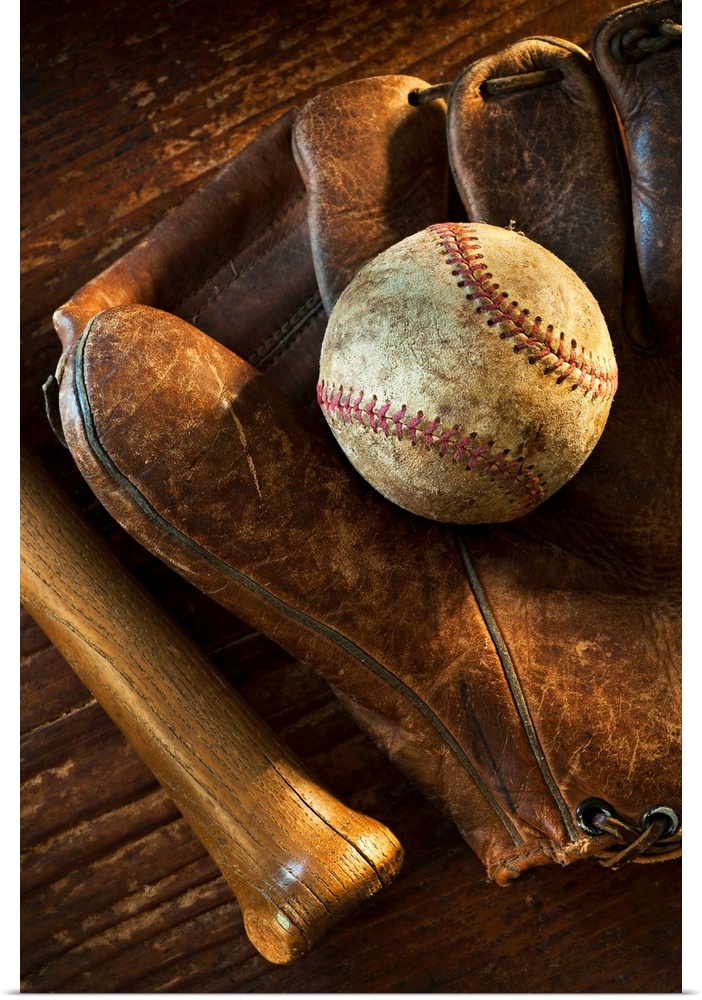 Wall docor of a worn baseball laying on top of an old baseball mit with a wooden bat next to it.