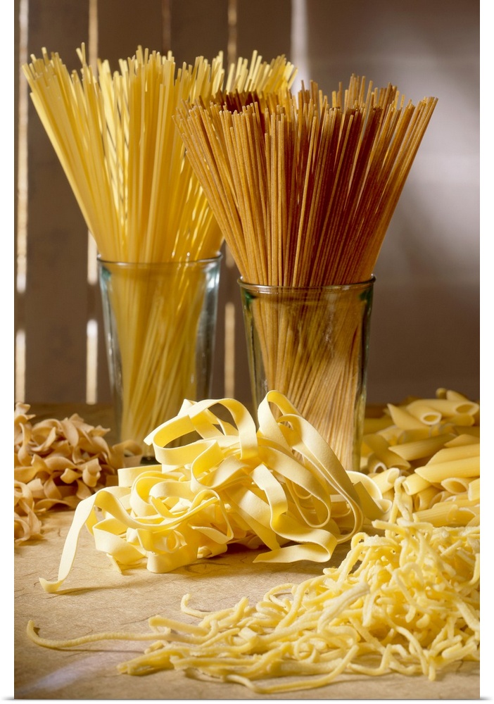 Dry pasta in glass jars and fresh pasta scattered in front of it is photographed artistically.