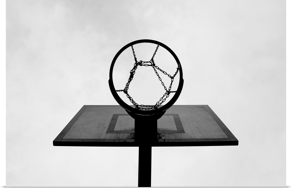 This is a monochromatic, horizontal photograph taken from below an outdoor basketball hoop.