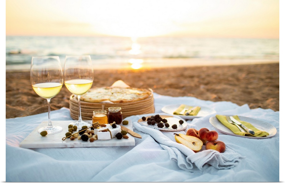 Beautiful served picnic at seaside on sunset. Romantic picnic for two with fruits, snacks, white wine and cheese pizza on ...