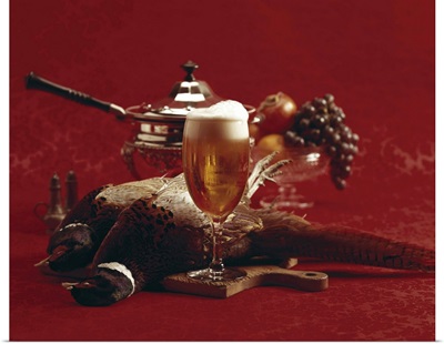 Beer glass and pheasant on chopping board, close-up