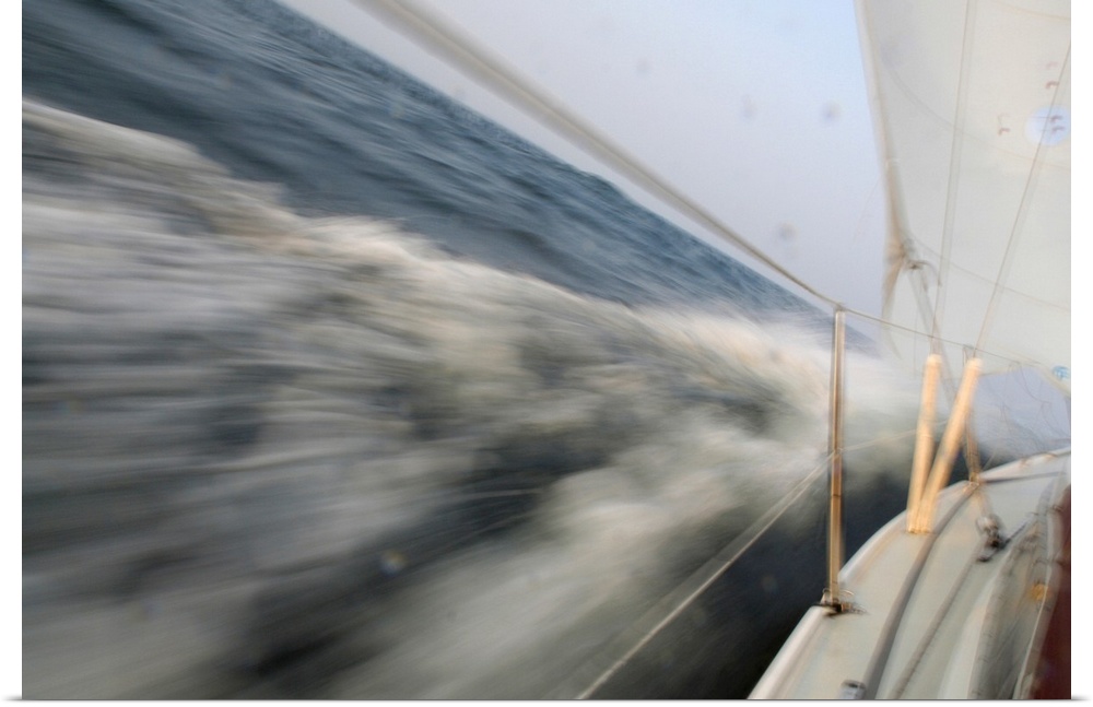 Action photo from the deck of a sailboat leaning into the ocean as it makes a sharp, fast turn.