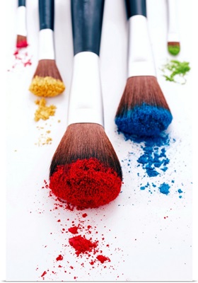 Brightly coloured eyeshadow powders on eyeshadow brushes, close-up