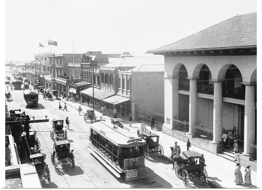 Carriages, trolleys, and pedestrians crowd a busy street in Kingston, Jamaica.