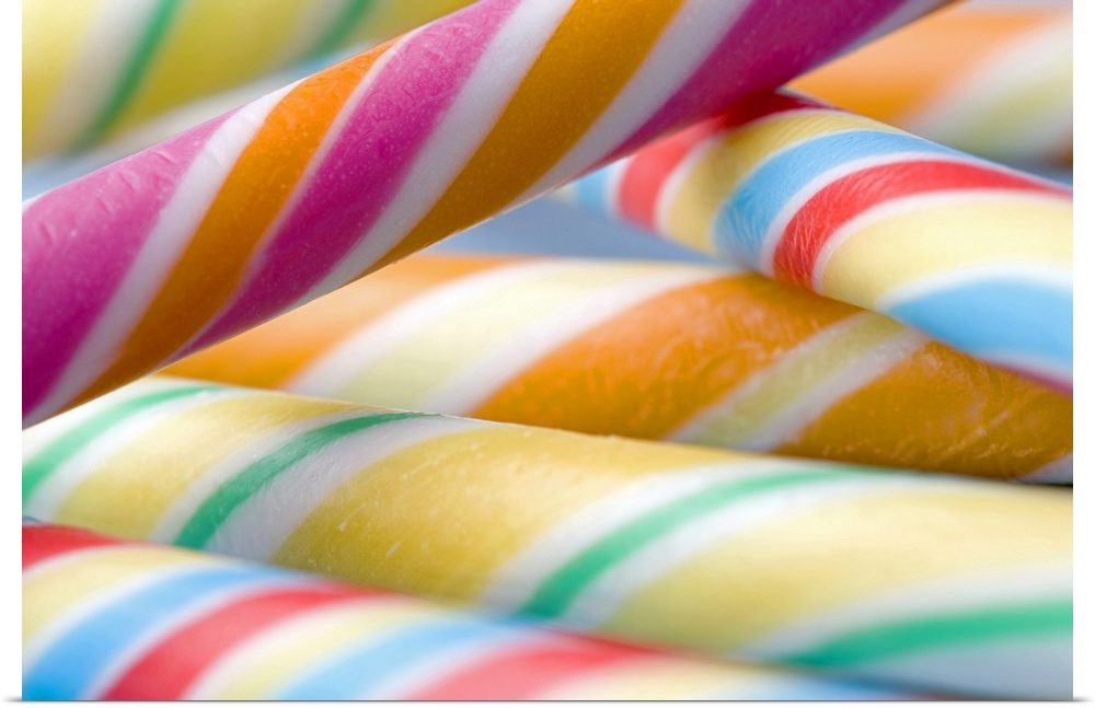 Landscape, large, close up photograph of multi-colored candy sticks, stacked in a small pile.