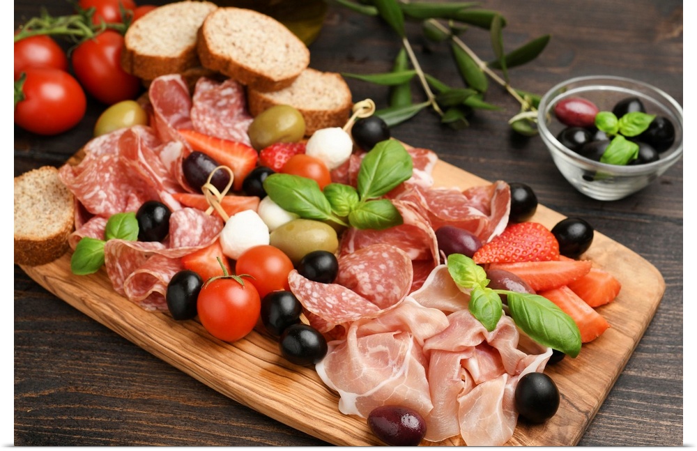 Charcuterie board salami, prosciutto, with green and black olives, appetizers with mozzarella balls, cherry tomatoes, and ...