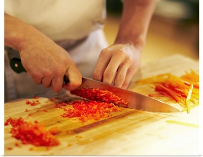 Chef mincing bell peppers with knife