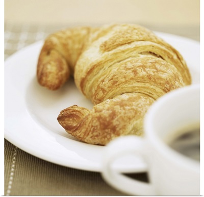 close-up of a cup of hot black coffee and a croissant