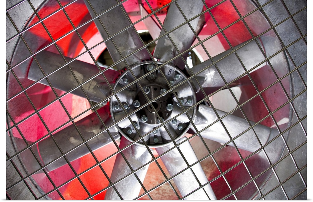 Close-up of an industrial ventilation fan with red hues lighting up the back.