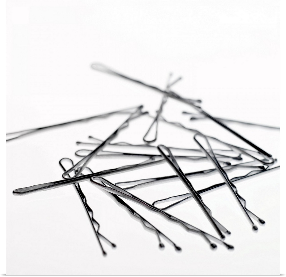Square, large close up photograph of a small pile of hair pins or bobby pins, on a plain white background.