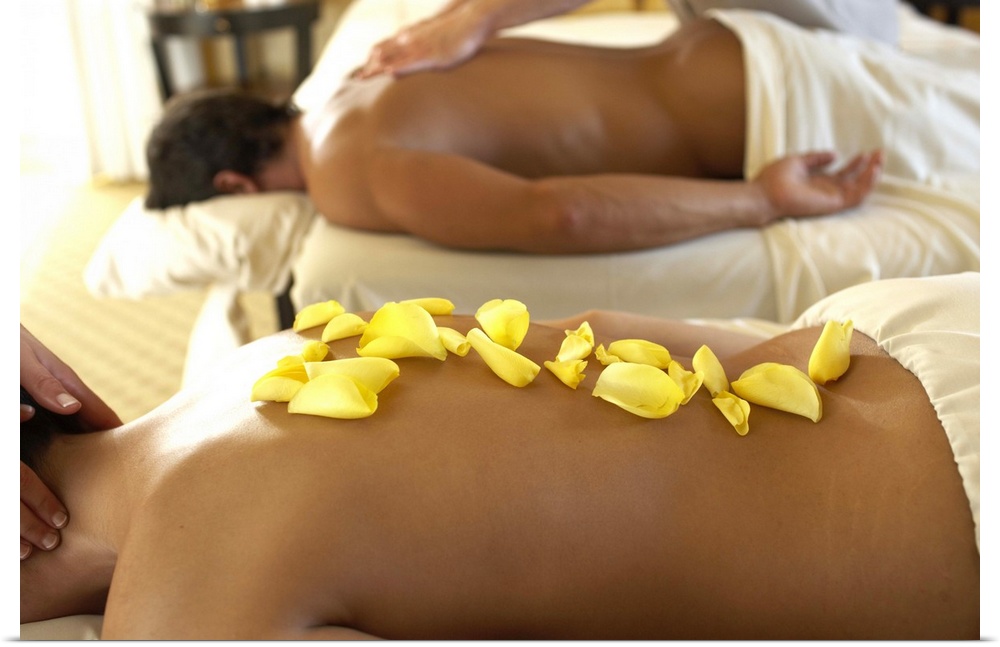 Couple receiving massage by two masseurs