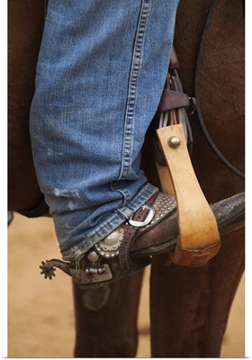 Cowboy boot in horse stirrup with spurs