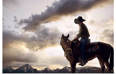 Cowboy on horse looking at mountain range, dusk, low angle view