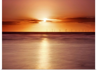Crosby beach, golden sunset with windfarm turbines and long exposure sea.