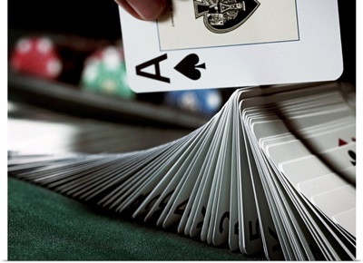 Croupier turning pack of cards on gaming table with ace, close-up