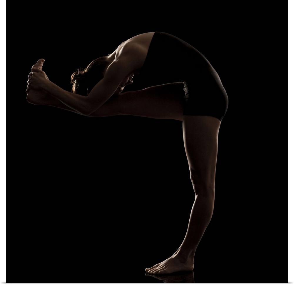 Studio shot of young woman practicing yoga.  The standing head to knee pose, dandayamana janushirasana.