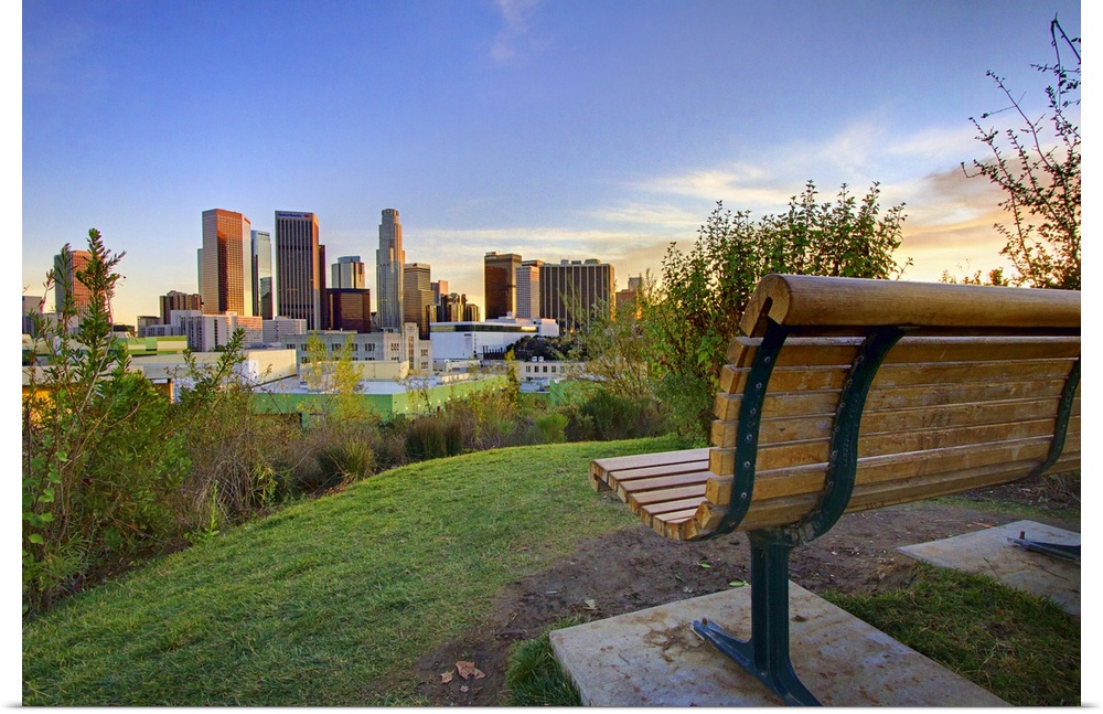 Photograph of park bench overlooking city skyline at dusk.