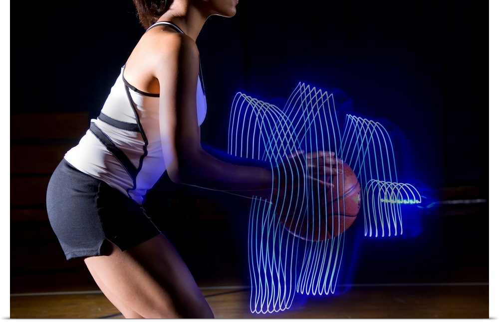 Female basketball player holding ball with surrounding light trail, side view, mid section, digital composite