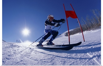 Female skier skiing around red gate, low angle view
