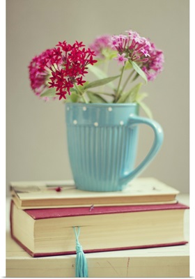 Flowers in blue cup on two books.