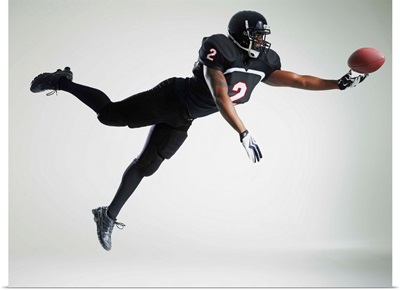 Football player leaping in mid air to catch ball