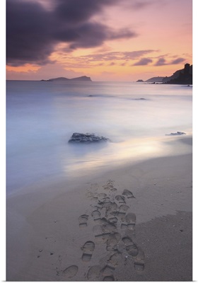 Footprints on beach at sunset.