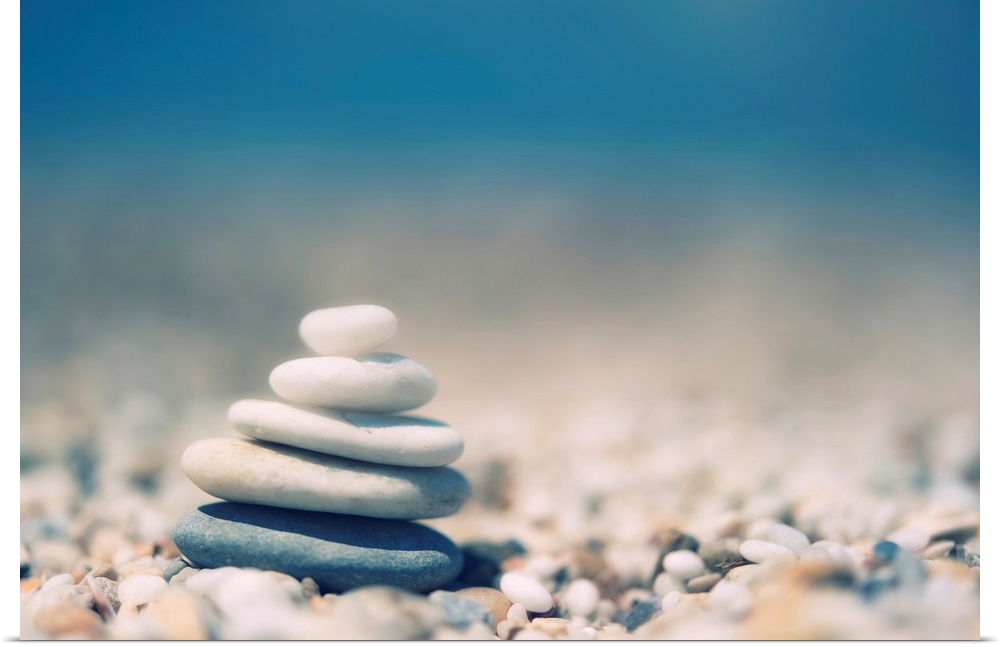 Up-close photograph of stacked smooth stones balancing on a bed of smaller pebbles.