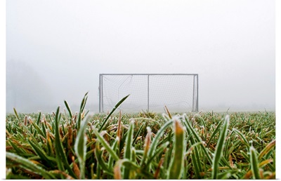 Frost and fog and football goal on soccer field.