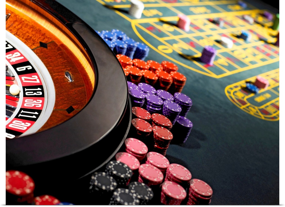 Gambling chips stacked around roulette wheel on gaming table