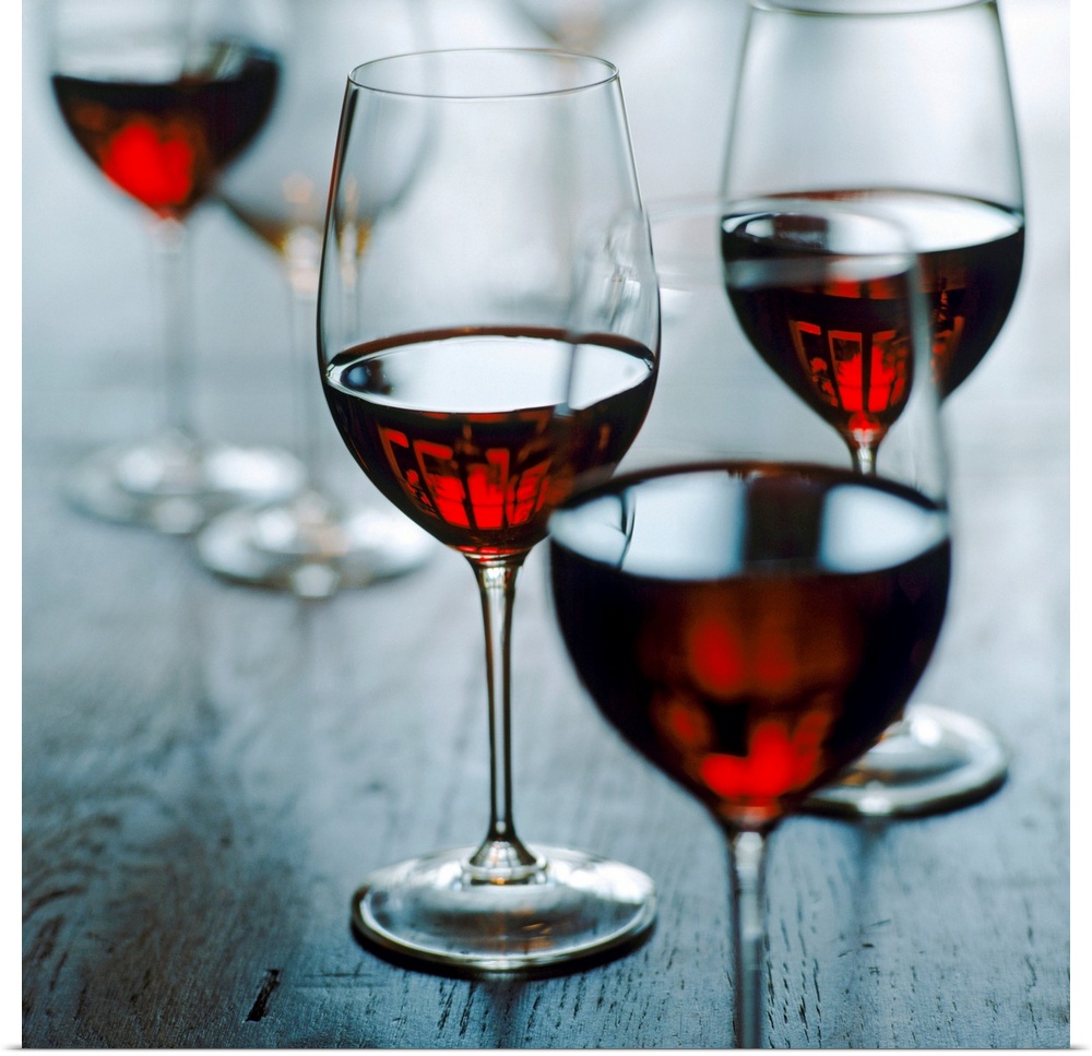 Photograph of half full wine glasses on wooden table.