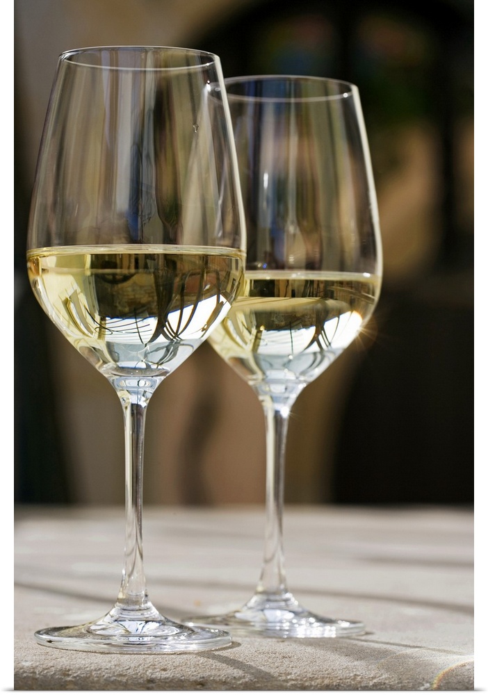 Up-close photograph of two champagne glasses half full on concrete table.