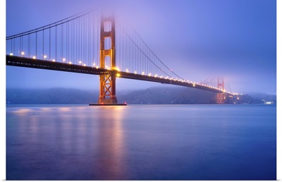 Golden gate bridge in San Francisco at dusk, bridge lights light up low fog.