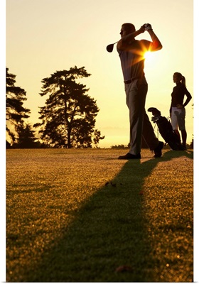 Golfers playing golf at sunset, low angle view