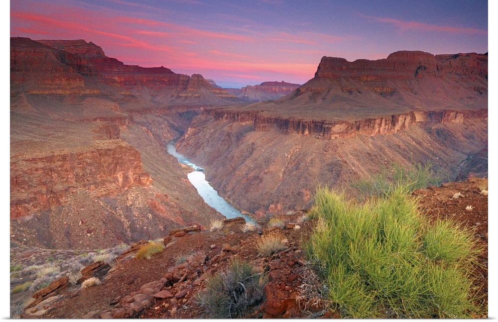 The sun rises on the red rocks of the Grand Canyon as the Colorado River roars down below.