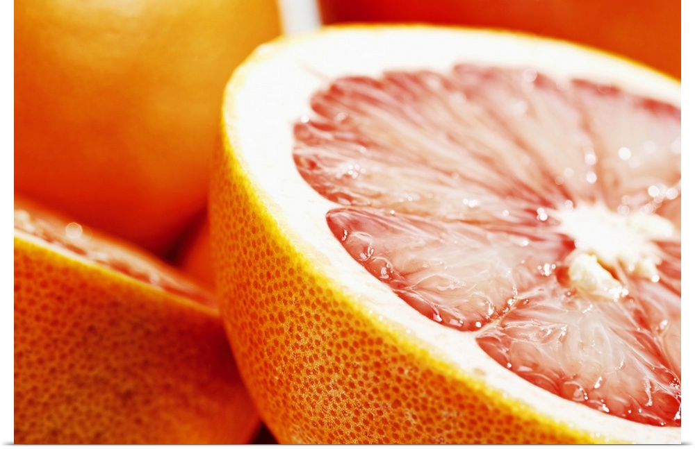 Big, landscape, close up photograph of a grapefruit, sliced perfectly in half, the other half and some whole grapefruits i...