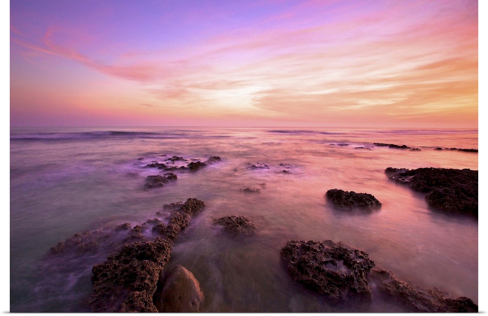 Purple clouds spreading above Wanliton sky at dusk and sea water crashing on coral reefs; in Pingtung, Taiwan.