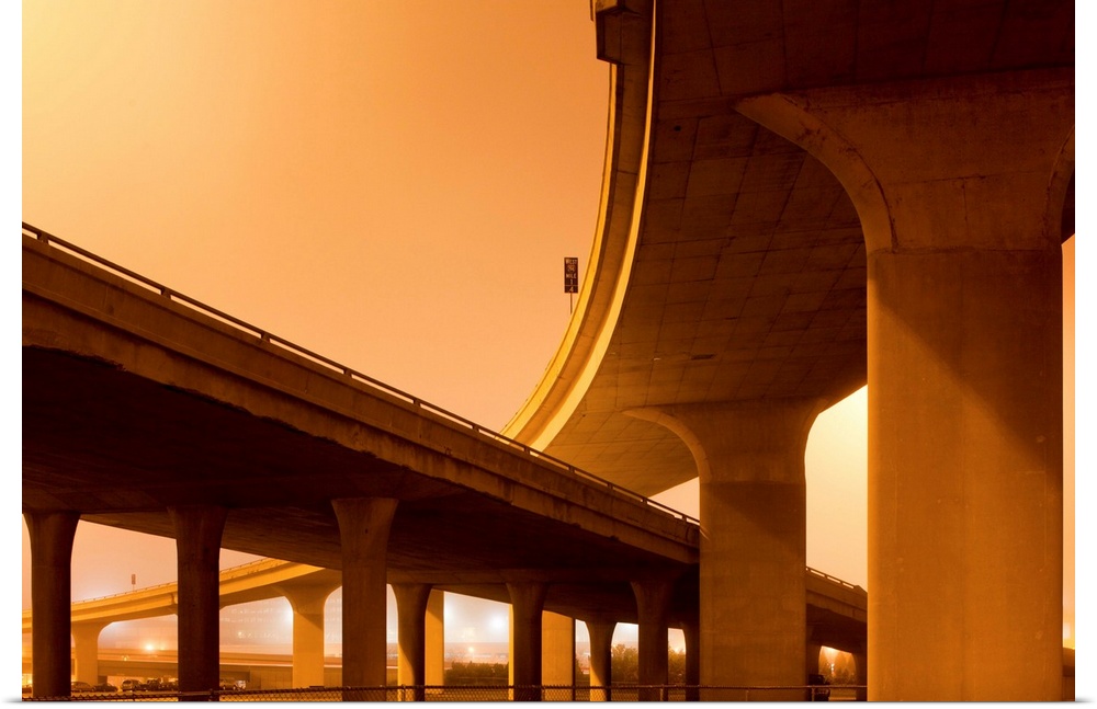 Concrete supports of towering highway overpasses leading into downtown on a foggy spring night.