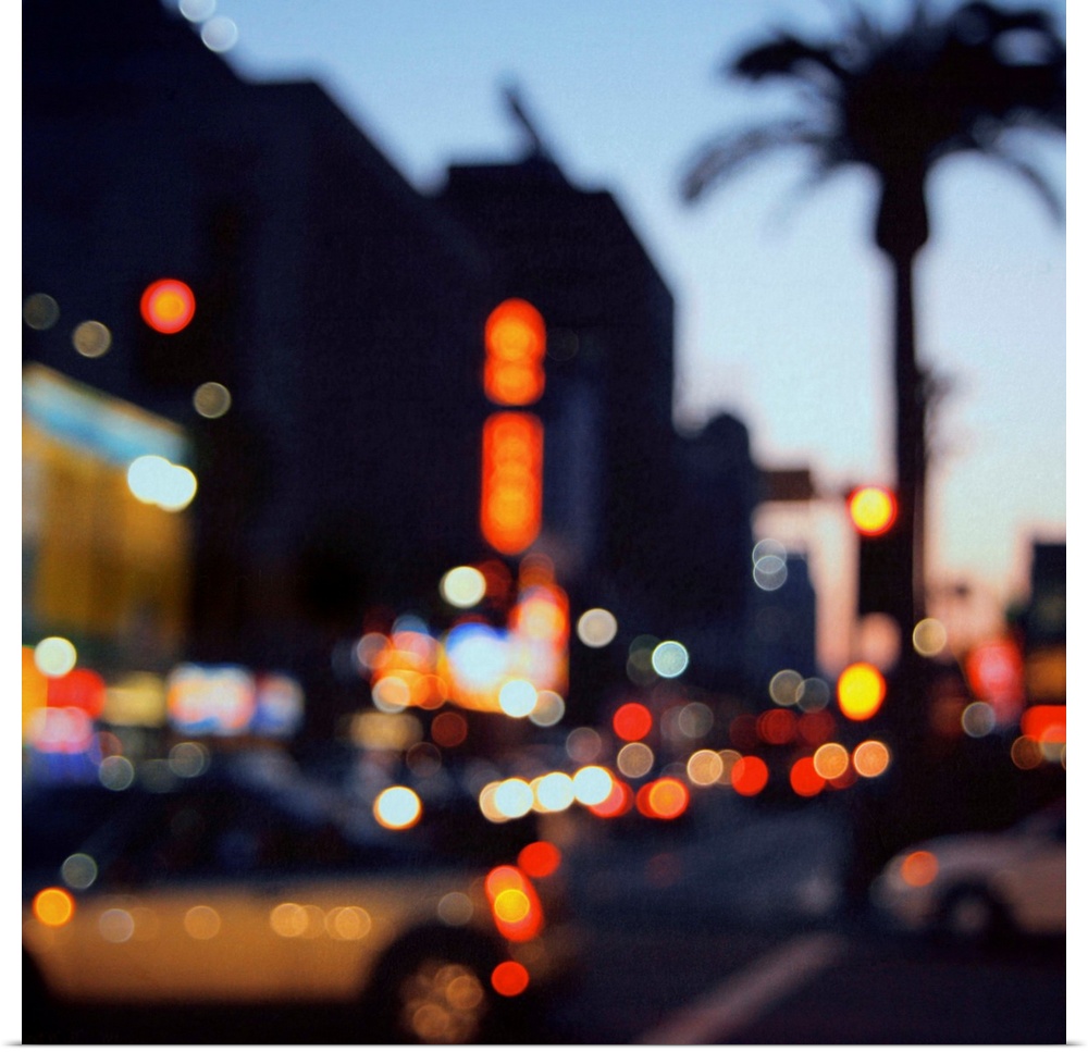 Out of focus image of Hollywood Boulevard at sunset. Bokeh lights, flash cars and palm trees