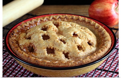 Home baked apple pie on cooling rack with apple and rolling pin