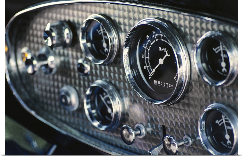 Horizontal, close up photograph on a big canvas of a chrome and black, rounded instrument panel on an antique car.