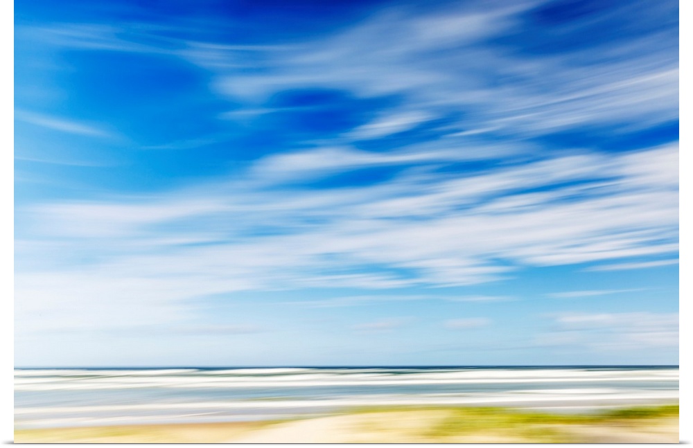 Intentional camera movement of ocean scene of with bright blue sky and wispy clouds. Teewah Beach, Queensland, Australia.