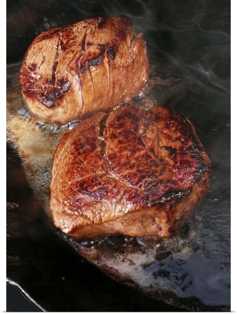 Fillet steaks sizzling in frying pan, close-up