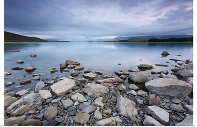 Lake Tekapo in New Zealand, with rocks in foreground during morning cloud.